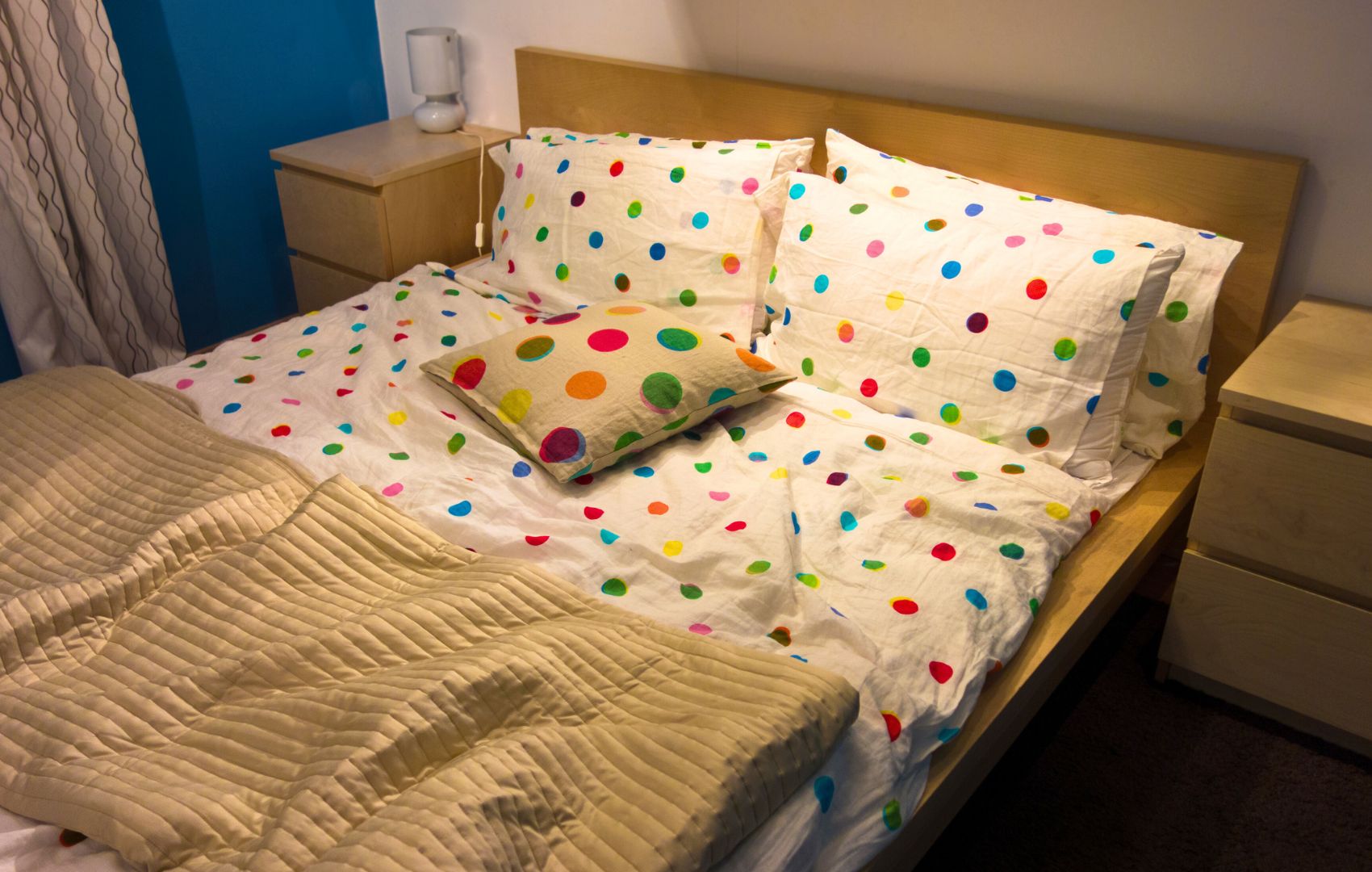 Bed room with colorful polka dot sheets and blue walls. 